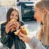 Two,Attractive,European,Women,Eat,Street,Fast,Food,While,Sitting
