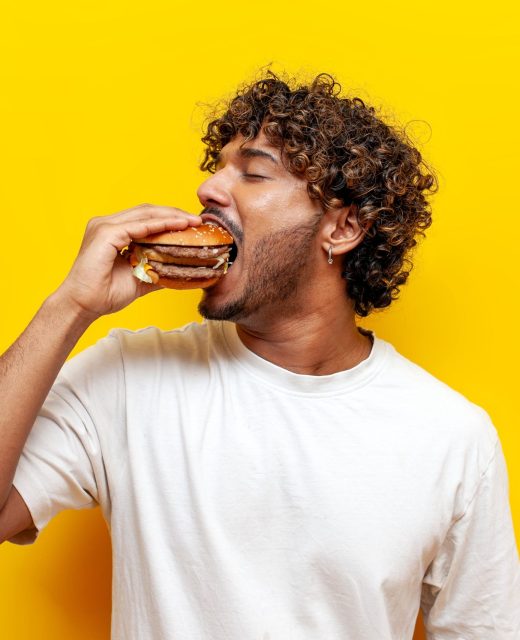 Hungry,Indian,Guy,Eats,A,Delicious,Burger,On,A,Yellow